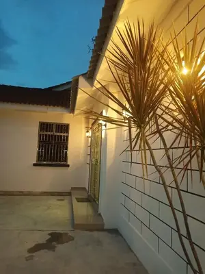 a white house with a palm tree in front of it at Pantai Remis Homestay 118A in Pantai Remis
