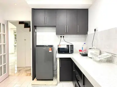 a kitchen with black cabinets and a refrigerator at Garden view bangalow wedding 12pax in Butterworth