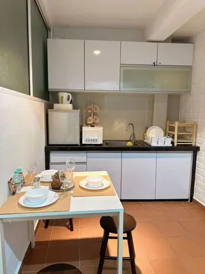 a kitchen with white cabinets and a table with plates on it at The Family Suit in George Town