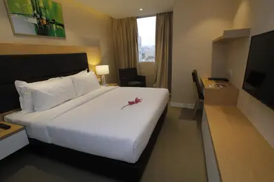 a hotel room with a large white bed and a desk at Hotel Excelsior Ipoh in Ipoh
