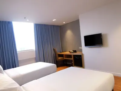 a hotel room with two beds and a desk at Hotel Excelsior Ipoh in Ipoh