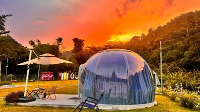 a dome tent in a field with a sunset in the background at The Starry Dome Family Room 2A 2K in Cameron Highlands