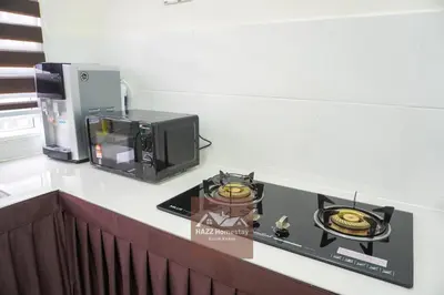 a kitchen counter with a stove and a microwave at HAZZ Homestay Kulim in Kulim