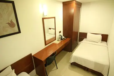 a hotel room with a bed and a desk with a mirror at AG Hotel Penang in George Town
