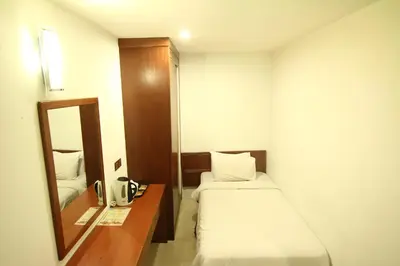 a small room with two beds and a mirror at AG Hotel Penang in George Town