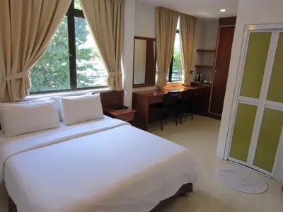 a bedroom with a large white bed and a desk at AG Hotel Penang in George Town
