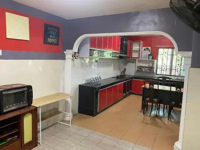 a kitchen with red cabinets and a table and chairs at Humayyah Homestay in Sungai Besar
