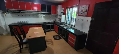 a kitchen with red and black cabinets and a wooden table at Humayyah Homestay in Sungai Besar