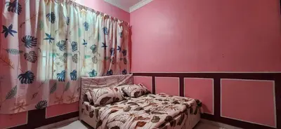 a bedroom with a bed and a pink wall at Humayyah Homestay in Sungai Besar