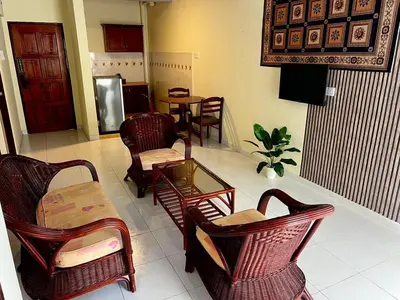 a living room with chairs and a table and a room with at Thara Beach Resort in Pasir Bogak