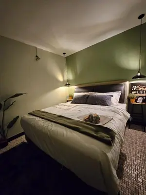a bedroom with a large white bed with a green wall at 85 Boutique Hotel in Ipoh