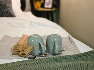 two green candles on a tray on a bed at 85 Boutique Hotel in Ipoh