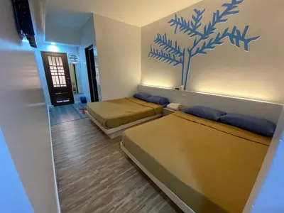 a room with two beds and a wall with a tree on it at Suria Cameron Hotel in Tanah Rata