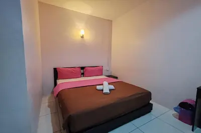 a small bedroom with a bed with pink pillows at Hotel Kuang Hua Sitiawan Near To UniKL-MIMET in Sitiawan