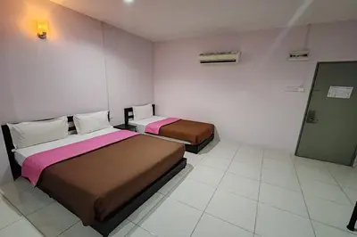 a room with two beds and a door in it at Hotel Kuang Hua Sitiawan Near To UniKL-MIMET in Sitiawan