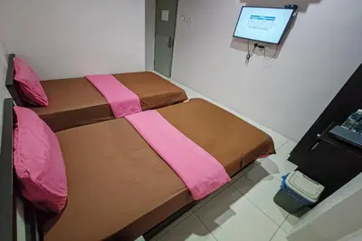 a bedroom with two beds and a computer monitor at Hotel Kuang Hua Sitiawan Near To UniKL-MIMET in Sitiawan
