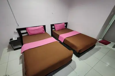 two beds sitting next to each other in a room at Hotel Kuang Hua Sitiawan Near To UniKL-MIMET in Sitiawan