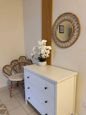 a white dresser with a vase of flowers on top at Orked Homestay Bagan Serai in Bagan Serai