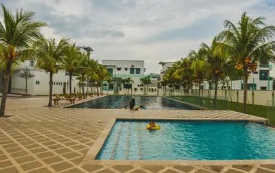 a pool with palm trees and a person in a raft at 8Pax comfortable setia residen in Sitiawan