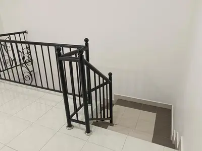 a staircase with a black railing next to a wall at 8Pax comfortable setia residen in Sitiawan