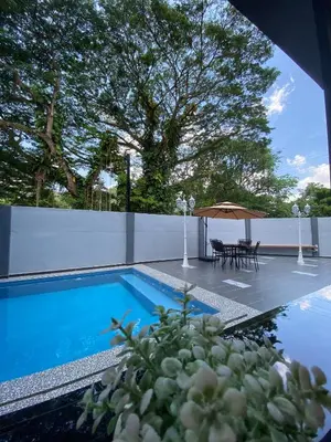 a swimming pool with a table and a umbrella at LYL Jaccuzi Private Pool House - 16PAX in Ipoh