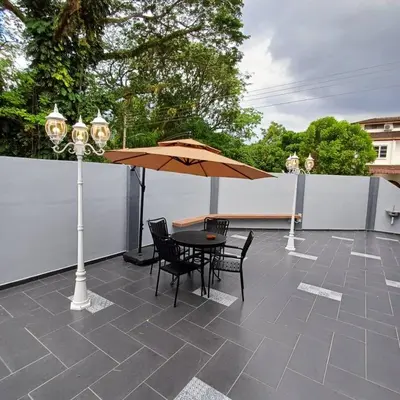 a patio with a table and chairs and an umbrella at LYL Jaccuzi Private Pool House - 16PAX in Ipoh