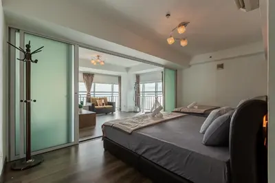 a bedroom with a large bed and a living room at Maritime Seaview Comfy Suite Penang with TVbox,Pool,Freewifi,2-8pax in Jelutong