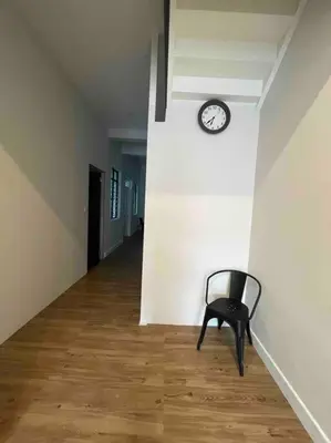 a black chair sitting in a hallway with a clock on a wall at Modern Victorian Homestay in Jelutong