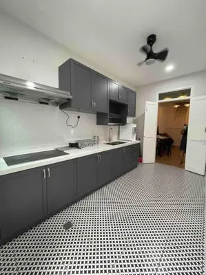 a kitchen with black cabinets and a black and white tile floor at Modern Victorian Homestay in Jelutong