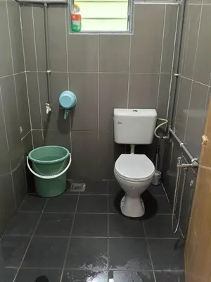 a bathroom with a toilet and a green bucket at Sal Homestay in Slim River
