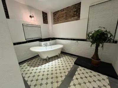 a bathroom with a white tub and a potted plant at THE GARDEN SUITE in Balik Pulau