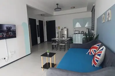a living room with a blue couch and a kitchen at Aesthetic Urban Suite With Infinite Pool & Gym in Jelutong
