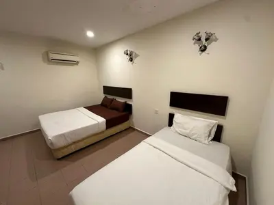 a bedroom with two beds and two lights on the wall at Ezzy In Hotel in Seri Manjung