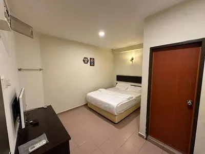 a bedroom with a bed and a desk and a door at Ezzy In Hotel in Seri Manjung