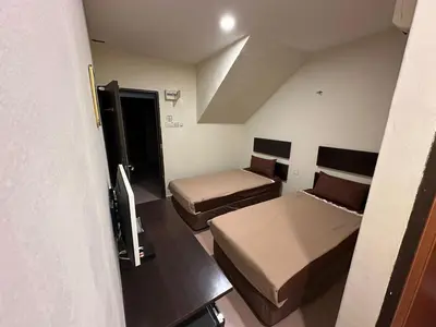 a small room with two beds and a tv at Ezzy In Hotel in Seri Manjung