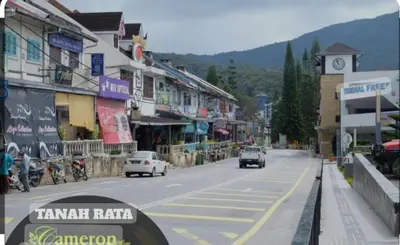 a street with cars driving down a street with a clock tower at Hillside cottage tanah rata in Tanah Rata