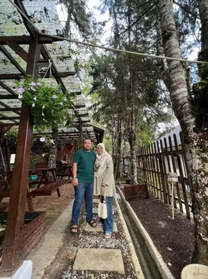a man and a woman standing next to a fence at Hillside cottage chalet studio in Tanah Rata