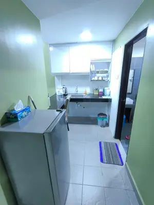 a kitchen with white cabinets and a white tile floor at ZH Studio Apartment Gua Musang With WIFI dan POOL in Gua Musang