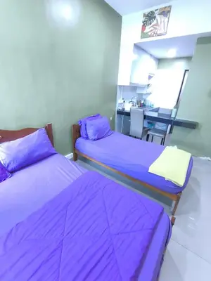 two beds in a room with purple sheets at ZH Studio Apartment Gua Musang With WIFI dan POOL in Gua Musang