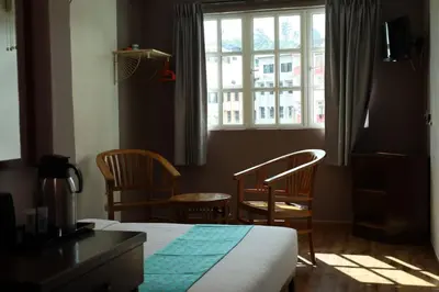 a bedroom with a bed and two chairs and a window at Hotel Sentosa in Brinchang