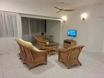a living room with wicker chairs and a television at Seaput Srisayang in Batu Ferringhi