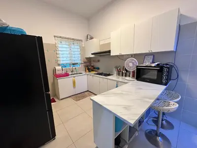 a kitchen with a white counter and a black refrigerator at Nurasyura Puncak Guesthouse in Seri Iskandar