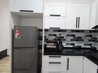 a kitchen with a stainless steel refrigerator and white cabinets at E! Best Apartment in Padang Serai