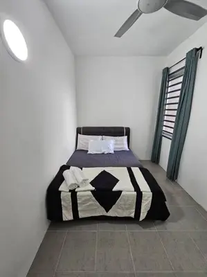 a bedroom with a bed with a black and white comforter at E! Best Apartment in Padang Serai