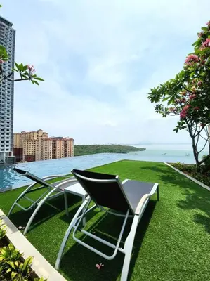 a table and chairs sitting on the grass near the water at Modern Luxe Island Suites #3BR in Jelutong