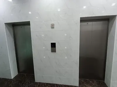 two elevators in a building with white tile walls at river hotel in Simpang
