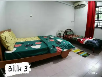 a bedroom with a bed with a green blanket at Homestay Mukhriz in Kulim