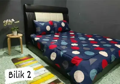 a bedroom with a bed with a blue comforter and a table at Homestay Mukhriz in Kulim