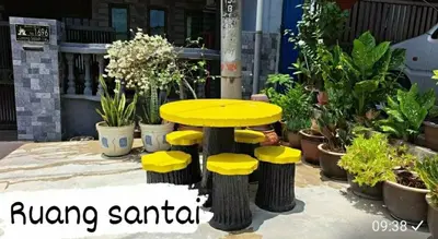 a yellow table and stools in front of plants at Homestay Mukhriz in Kulim