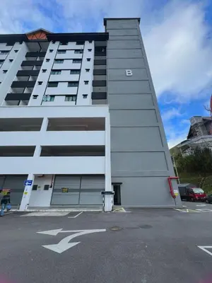 a tall white building with a parking lot at PMRTJ BY D Atas Bukit Antarium in Tanah Rata